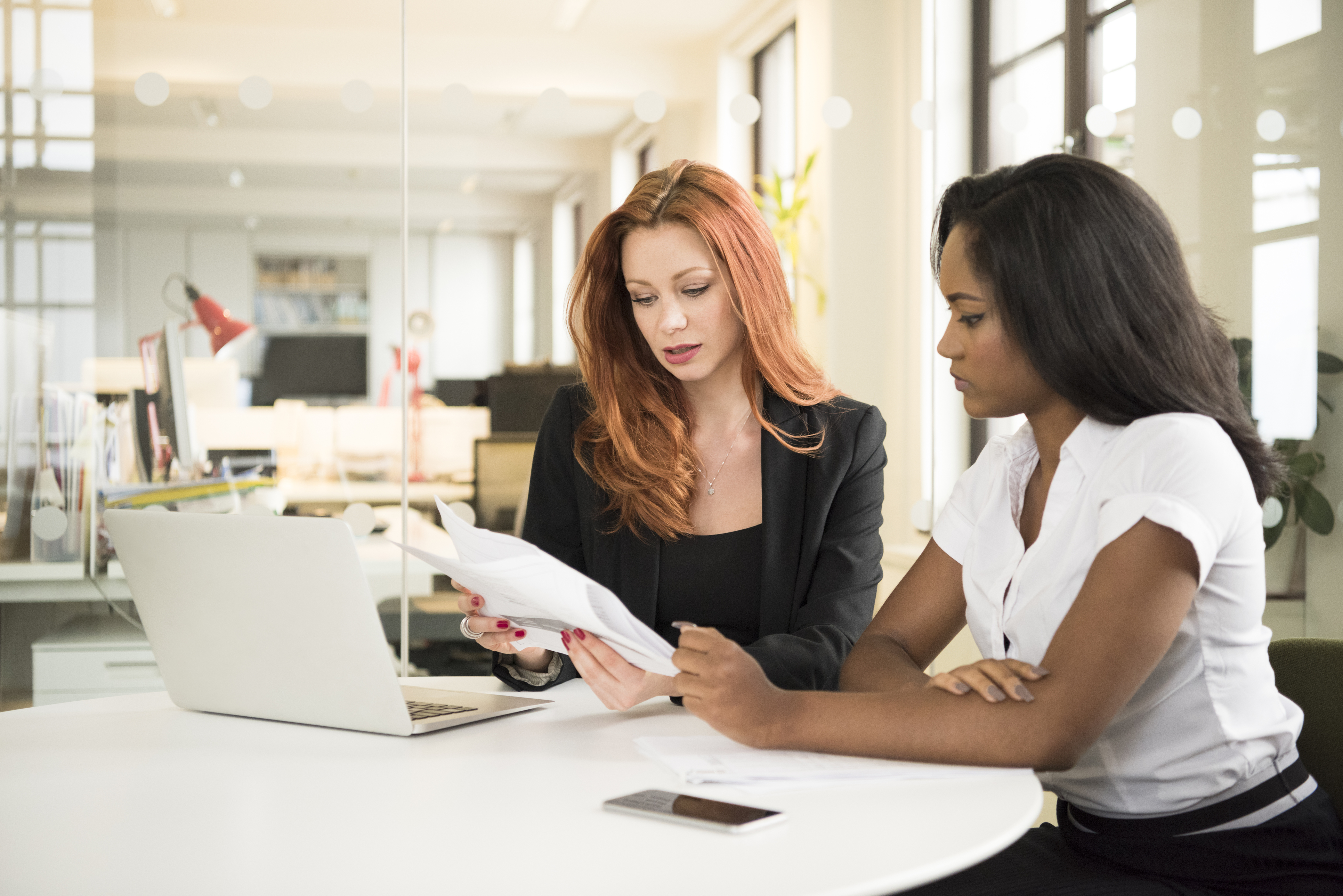 Female manager explaining documents to young businesswoman